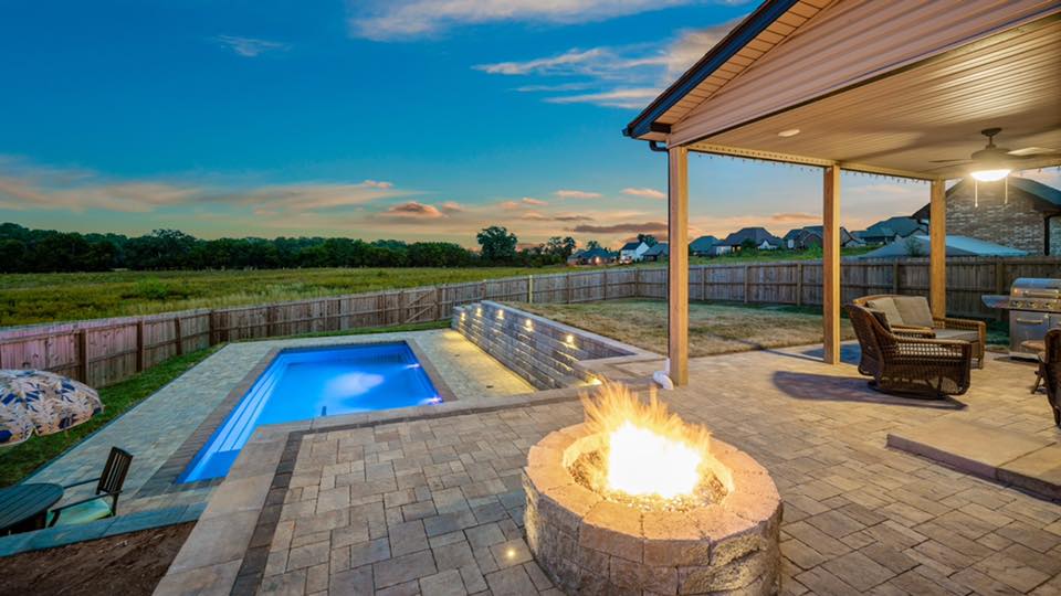 a fire pit patio and a pool in a backyard having beautiful concrete pool deck